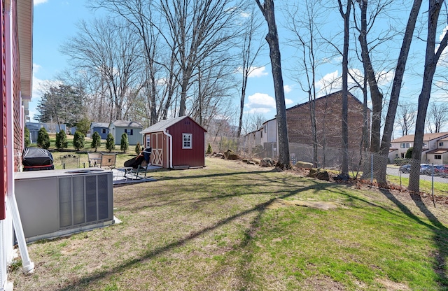 view of yard with central AC unit, an outbuilding, a residential view, a storage unit, and fence