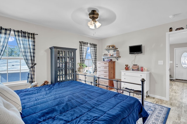 bedroom with baseboards, wood finished floors, ceiling fan, and multiple windows