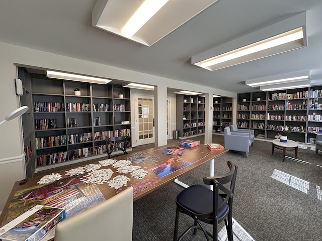 office area with wall of books, built in features, and carpet floors