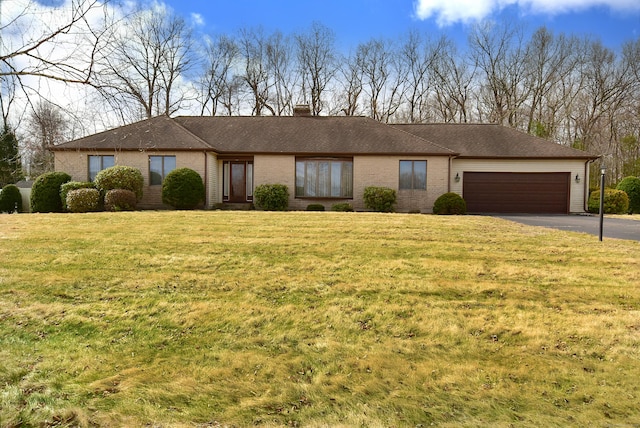 single story home featuring a front yard, driveway, a chimney, and an attached garage