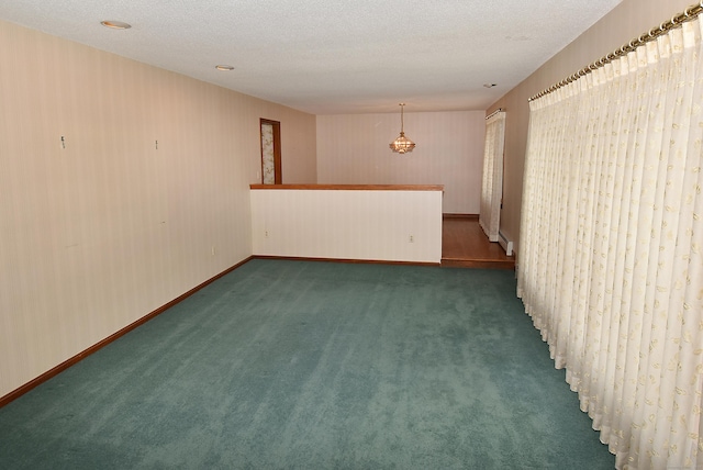 unfurnished room with a textured ceiling, baseboards, and carpet floors