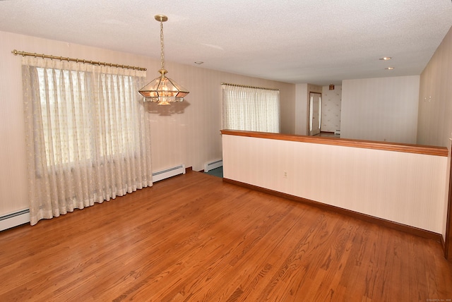 unfurnished room with a baseboard heating unit, a textured ceiling, and wood finished floors