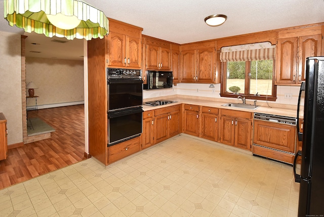 kitchen featuring a sink, light countertops, brown cabinetry, and black appliances