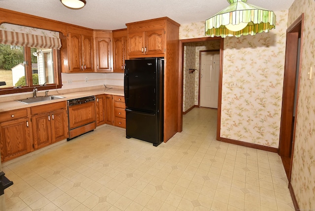kitchen with freestanding refrigerator, wallpapered walls, light countertops, a sink, and paneled dishwasher