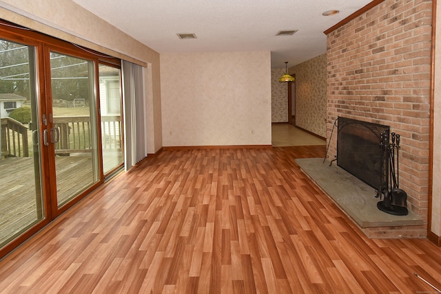 unfurnished living room with baseboards, light wood-type flooring, a fireplace, and visible vents