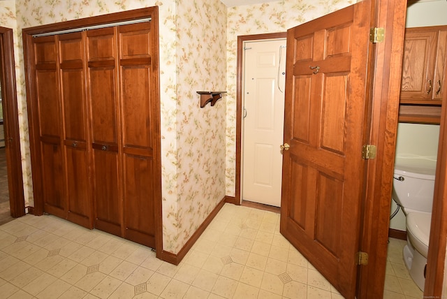 hallway featuring baseboards and wallpapered walls