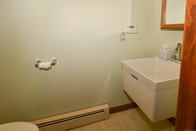 half bath featuring tile patterned floors, toilet, baseboards, and baseboard heating