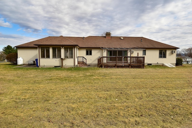 back of house featuring a yard, a wooden deck, a shingled roof, and a chimney