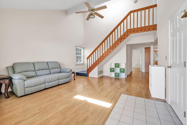 living room featuring high vaulted ceiling, visible vents, stairway, a ceiling fan, and light wood-style floors