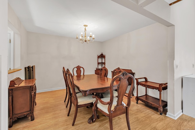 dining area featuring baseboards, light wood-style floors, and an inviting chandelier