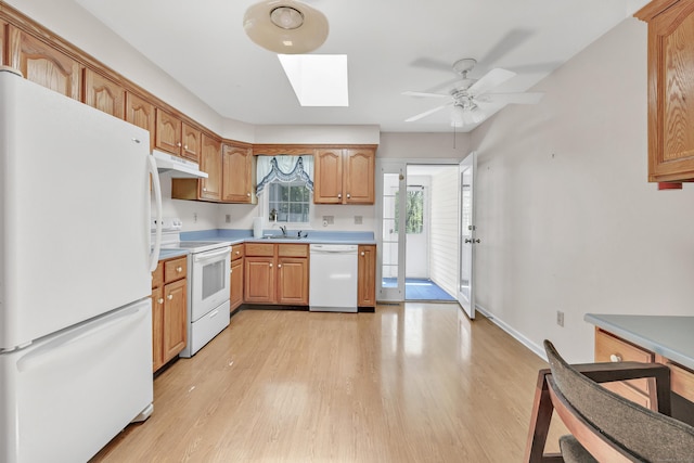 kitchen with a ceiling fan, under cabinet range hood, white appliances, light wood finished floors, and a skylight