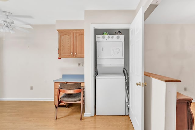 laundry room with a ceiling fan, baseboards, light wood finished floors, stacked washer and clothes dryer, and laundry area