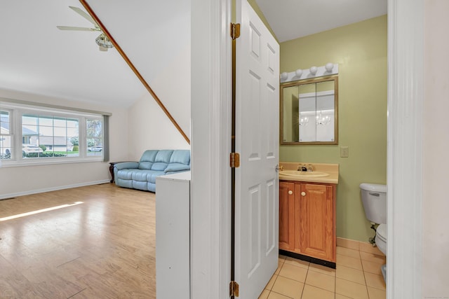 half bathroom with vanity, toilet, baseboards, and wood finished floors