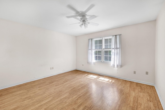 empty room with baseboards, light wood-type flooring, a ceiling fan, and visible vents