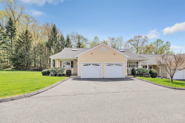 ranch-style home featuring a front lawn, driveway, roof with shingles, and an attached garage