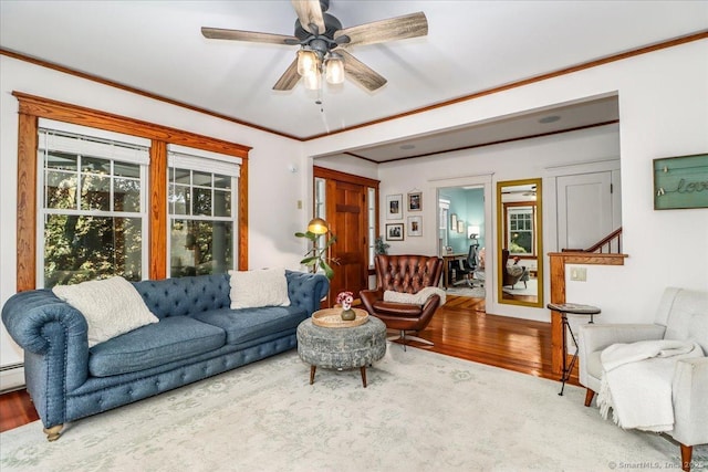 living area with crown molding, wood finished floors, a baseboard heating unit, and a ceiling fan