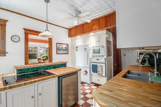 kitchen with white cabinets, white appliances, wooden counters, tile patterned floors, and a sink