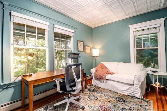 office area featuring baseboard heating, an ornate ceiling, and wood finished floors