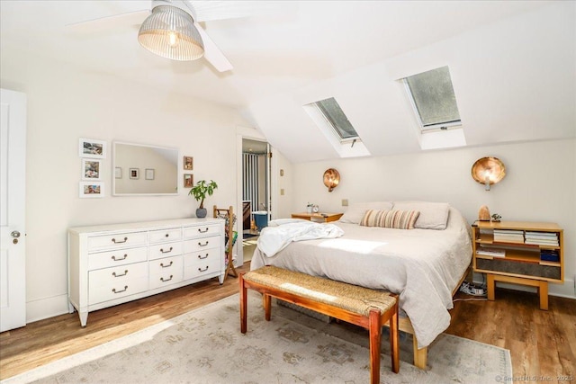 bedroom with vaulted ceiling with skylight, light wood-style floors, and ceiling fan