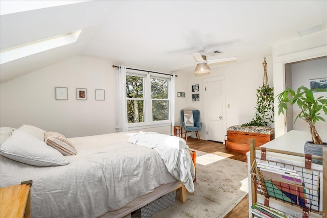 bedroom featuring wood finished floors, lofted ceiling with skylight, and a ceiling fan