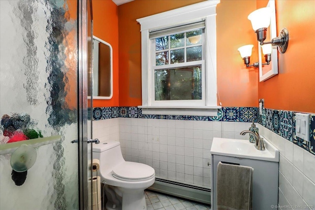 bathroom featuring vanity, tile walls, a baseboard heating unit, toilet, and wainscoting