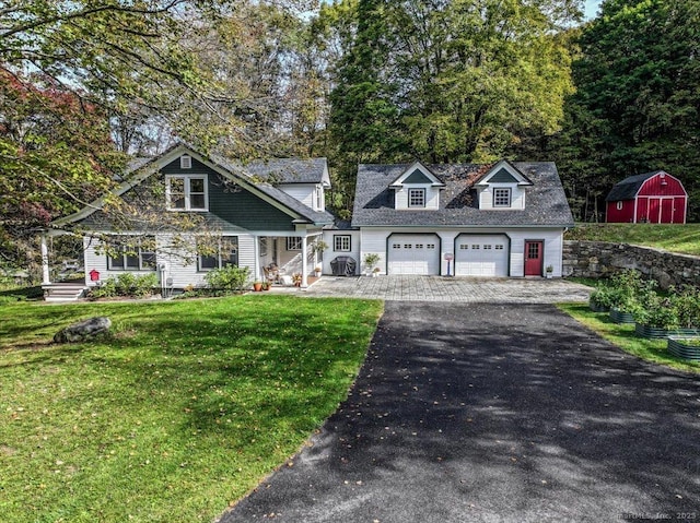 view of front of property with aphalt driveway, a storage shed, an attached garage, a front lawn, and an outdoor structure