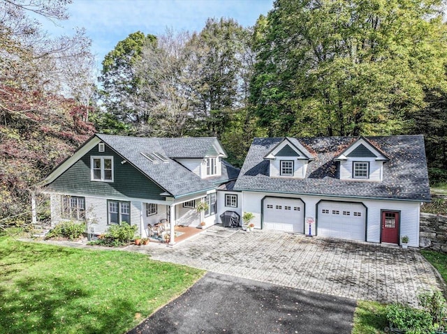 view of front facade featuring a shingled roof, a front yard, and aphalt driveway