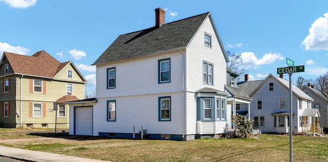 back of house featuring a lawn, a chimney, and a garage