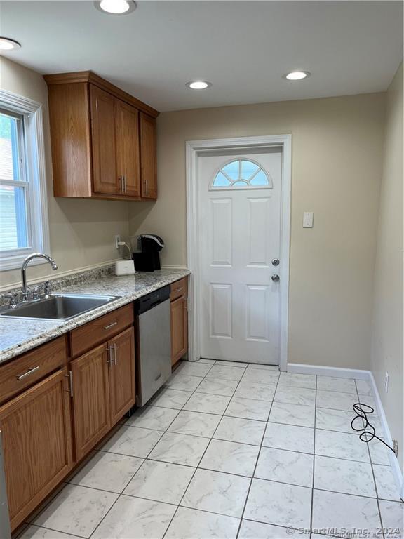 kitchen featuring stainless steel dishwasher, brown cabinets, recessed lighting, and a sink