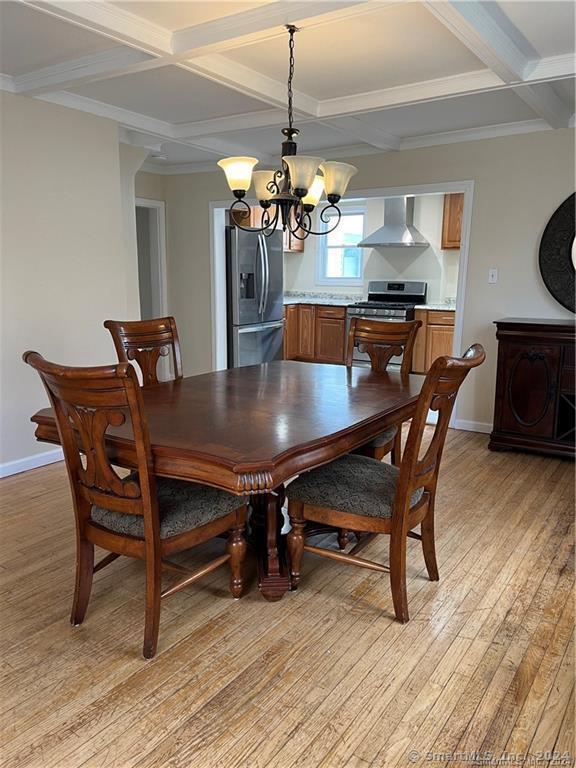 dining room featuring a notable chandelier, coffered ceiling, baseboards, and light wood-type flooring
