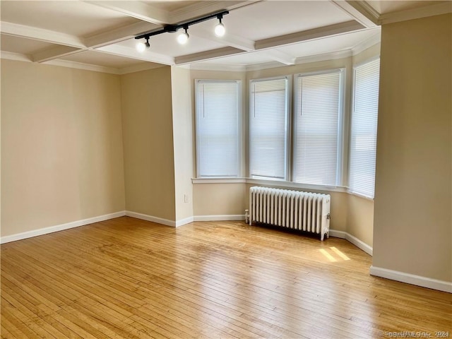 unfurnished room with light wood finished floors, baseboards, beam ceiling, and radiator heating unit