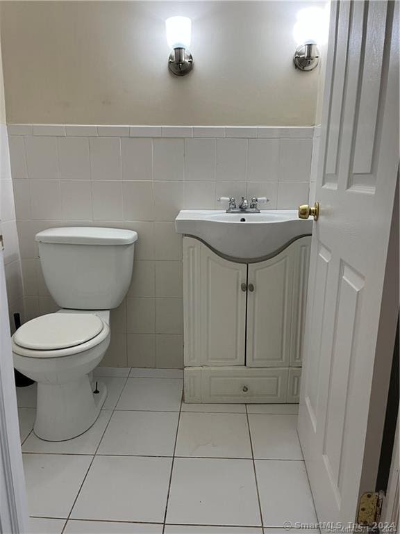 bathroom featuring toilet, a wainscoted wall, tile patterned floors, and tile walls