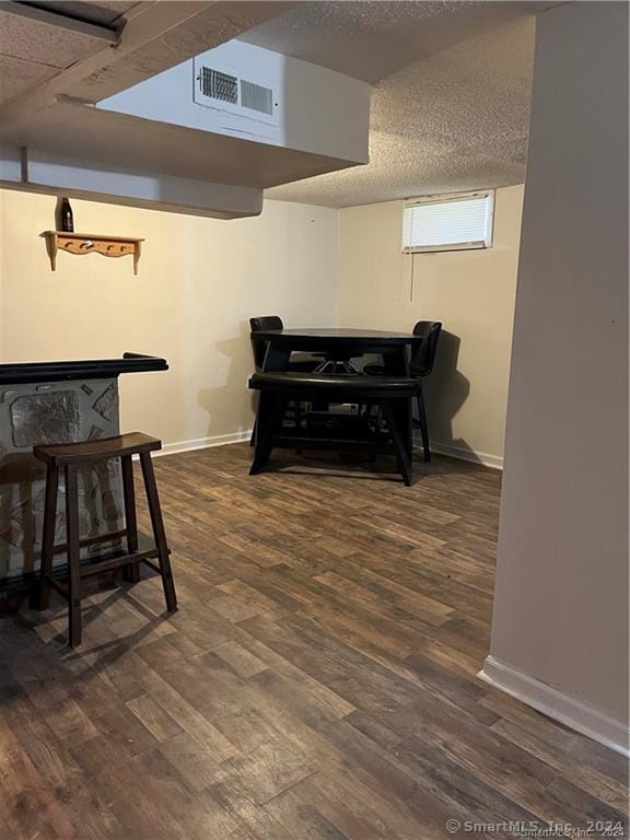 interior space with visible vents, a textured ceiling, baseboards, and wood finished floors