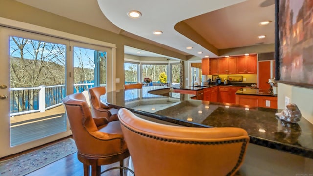 224 Tepi Dr, Southbury, CT 06488 - kitchen featuring recessed lighting, a breakfast bar, brown cabinets, a sink, and a peninsula
