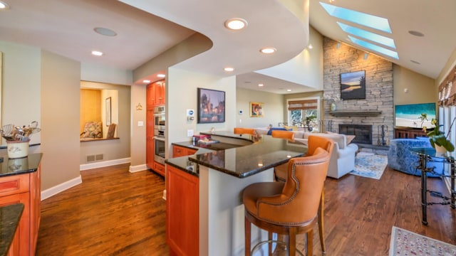 224 Tepi Dr, Southbury, CT 06488 - kitchen featuring baseboards, a breakfast bar area, a stone fireplace, dark wood-style floors, and visible vents