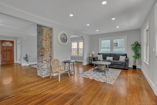 living area featuring ornate columns, baseboards, wood finished floors, and recessed lighting