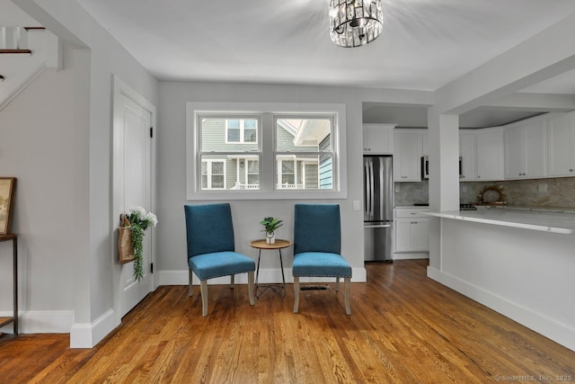 living area featuring a notable chandelier, baseboards, and wood finished floors