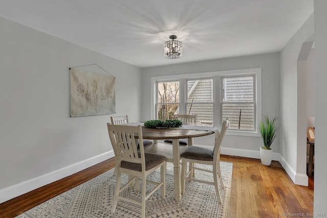 dining area with an inviting chandelier, baseboards, and light wood-style floors