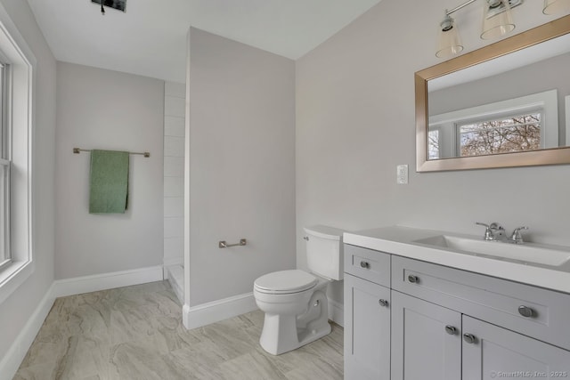 bathroom featuring toilet, vanity, walk in shower, marble finish floor, and baseboards