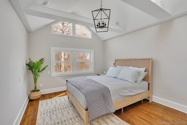 bedroom with an inviting chandelier, baseboards, lofted ceiling, and wood finished floors