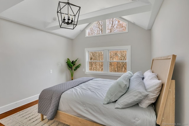 bedroom featuring baseboards, lofted ceiling, wood finished floors, and an inviting chandelier