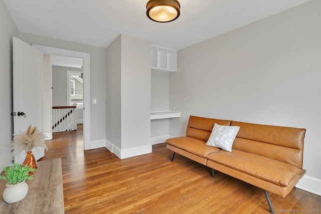 sitting room with baseboards, an upstairs landing, and wood finished floors