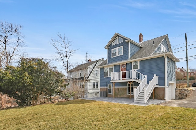 rear view of house featuring a lawn, a chimney, a patio, and stairway