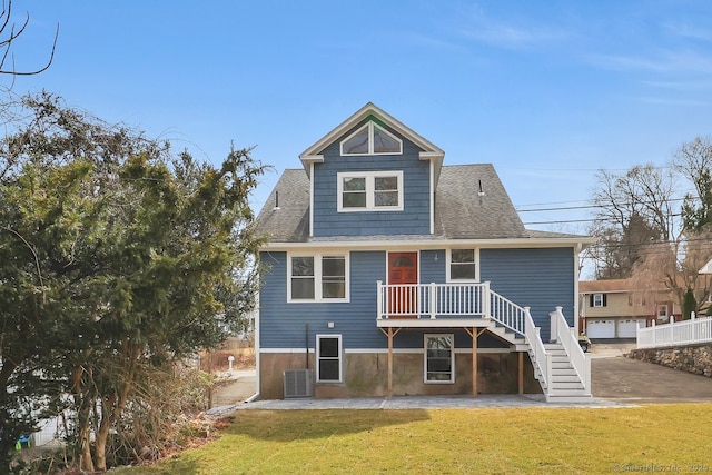 rear view of property with central AC unit, a lawn, a shingled roof, and stairway