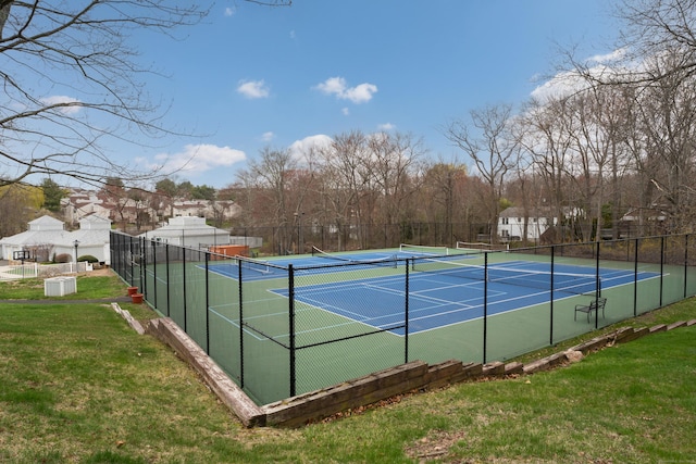 view of sport court with fence and a lawn