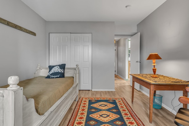 bedroom featuring a closet, baseboards, and light wood finished floors