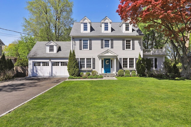 colonial house with driveway, a shingled roof, a front yard, and a garage