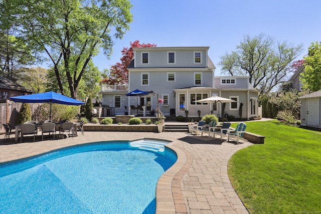 rear view of house featuring a lawn, a patio area, an outdoor pool, and outdoor dining space