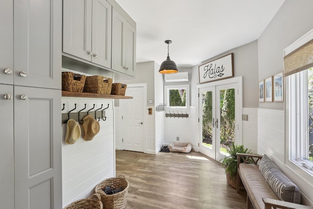 mudroom featuring a wainscoted wall, a wall unit AC, french doors, and wood finished floors