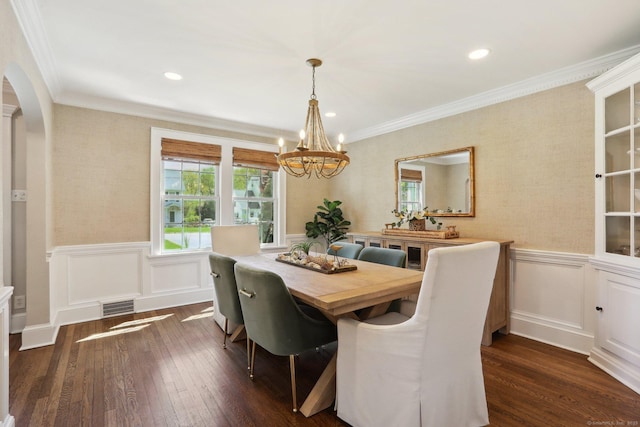 dining area featuring dark wood-style flooring, arched walkways, an inviting chandelier, and wainscoting